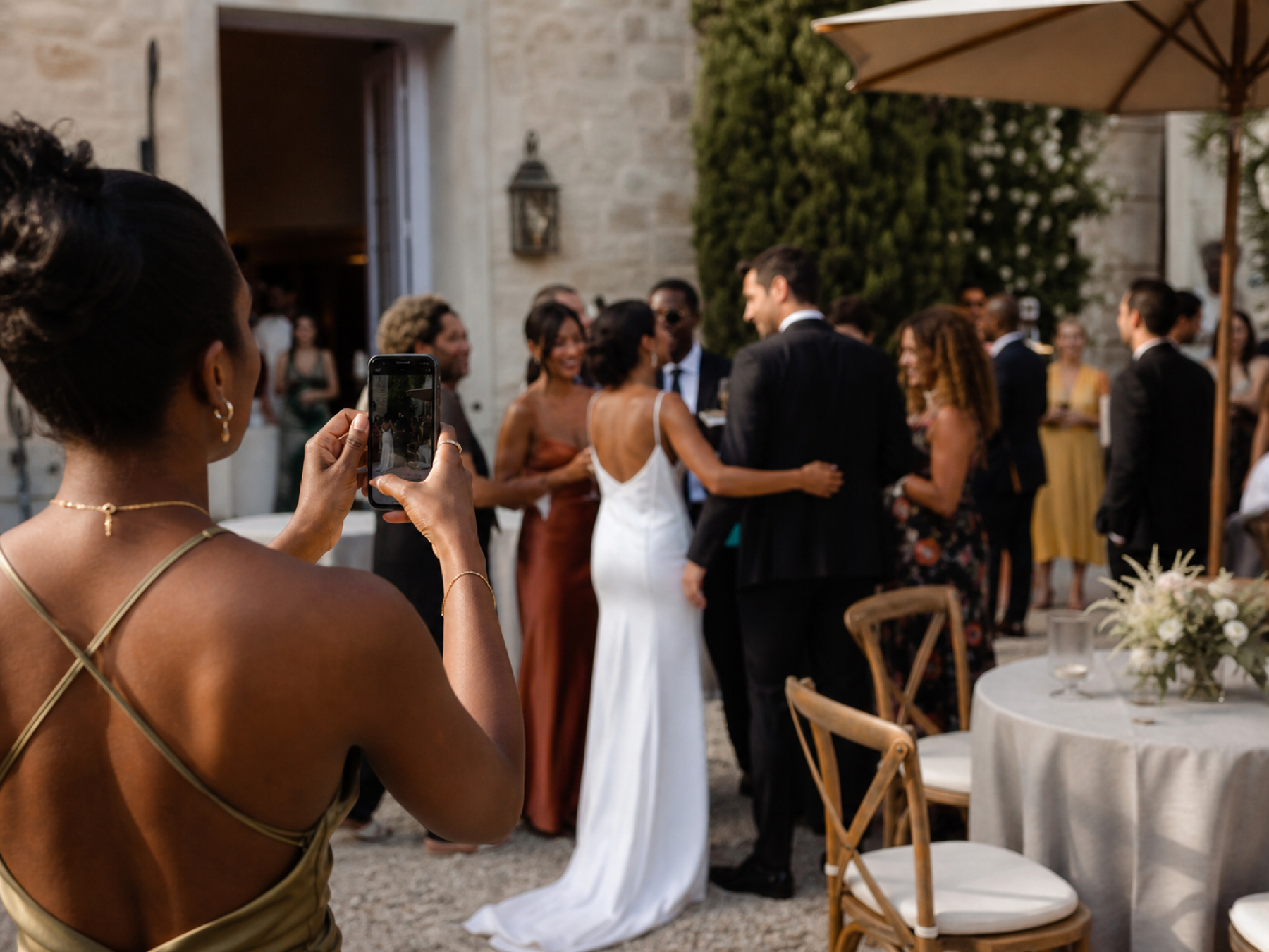 Wedding guests gathering outside a venue, with one guest taking a photograph on a phone.